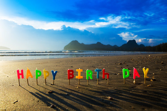 Happy birthday colorful candles on a beach.