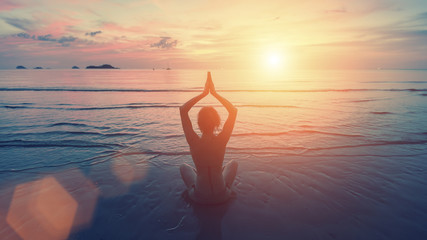 Yoga female silhouette. Woman doing meditation near the ocean.