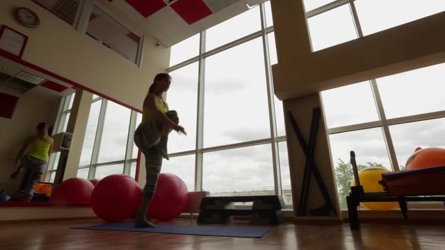 Young Girl Performs A Coach Nataradzhasana Asana (posture Dance God Or Cosmic Dancer Pose) - Pose To Balance Retention And Development Of The Vestibular Apparatus In The Fitness Room