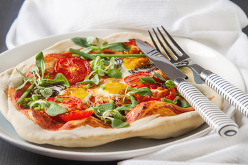 Home Italian pizza with tomato and quail eggs salad