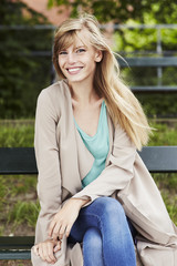 Naklejka na ściany i meble Beautiful woman smiling on park bench, portrait