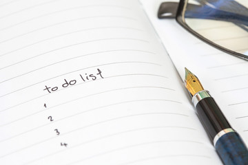 writing to do list on notebook page with pen on wood background
