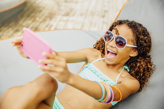 Mixed race girl taking selfie with cell phone on patio