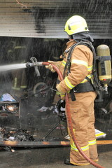 Melbourne, Victoria, Australia - 2011 July 10: Fire fighter spraying water on a garage on fire in an residential area of Glen Waverley in Melbourne east. - 118339236