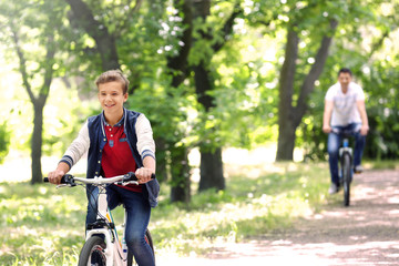 Cute boy with father on bike ride in park