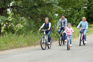 Happy family riding bikes on road