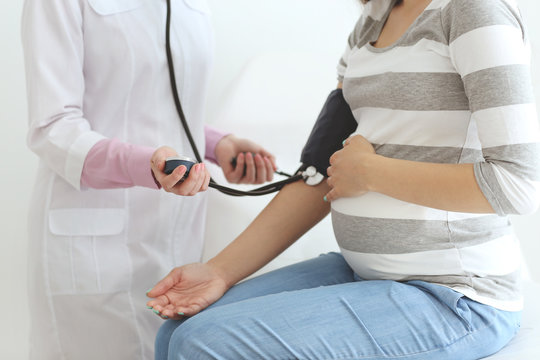 Doctor measuring pressure to a pregnant woman at the hospital