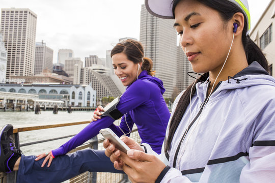 Runner using cell phone at waterfront, San Francisco, California, United States