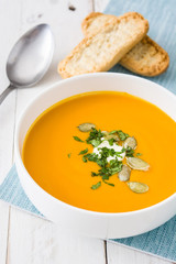 Pumpkin soup and ingredients on white wooden background

