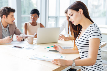 Fototapeta premium Concentrated young woman working with her business team in office