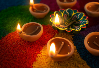 Diya lamp lit on colorful rangoli