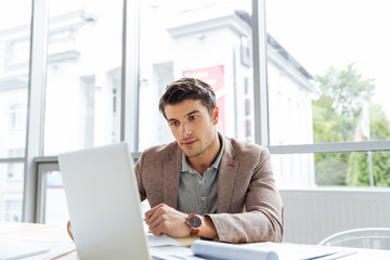 Thoughtful businessman working with laptop and thinking in office