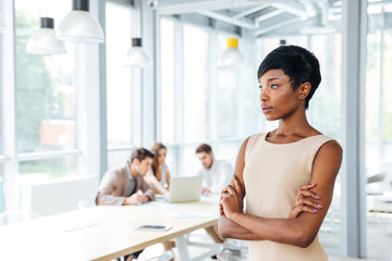 Pensive businesswoman standing with arms crossed and thinking in office