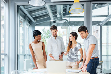 Successful business people with laptop standing and talking in office