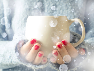 Tea in a cup. Falling snow. A girl holding a cup of tea