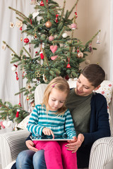Obraz na płótnie Canvas Mother and daughter using tablet PC near Christmas tree