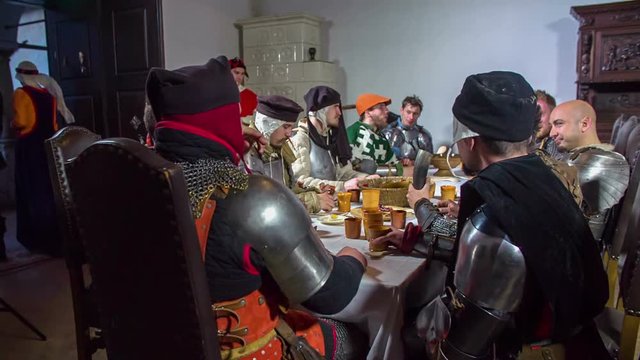 Members of the royal family leave a dining room and the knights start eating their dinner.
