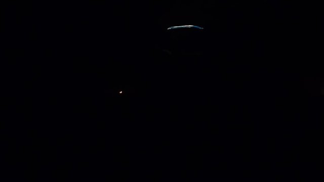 A man is swinging a whip which has fire on it. He is doing it also around his body. It is evening time.
