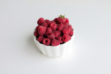 Fresh raspberry in white tipped bowl, closeup. Copy space.