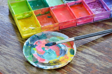 paint brush and oil color in plastic tray on wooden board
