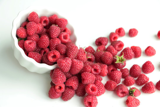 Fresh dropped raspberry in white tipped bowl, closeup. Copy space.