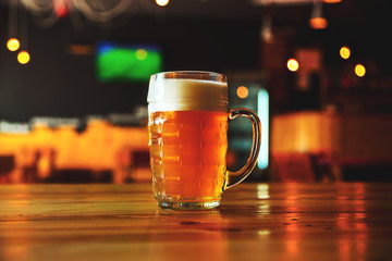Beautiful background of the Oktoberfest. Glass of cold fresh lager beer on a wooden bar counter in pub with free space for your text