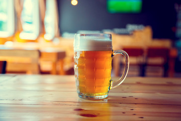 Beautiful background of the Oktoberfest. Glass of cold fresh lager beer on a wooden bar counter in pub with free space for your text