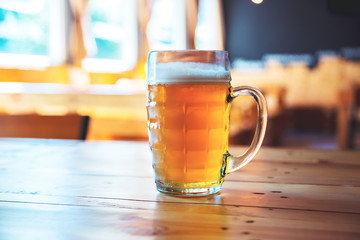 Beautiful background of the Oktoberfest. Glass of cold fresh lager beer on a wooden bar counter in pub with free space for your text