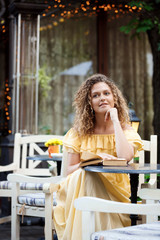 Young beautiful girl reading, sitting in cafe.