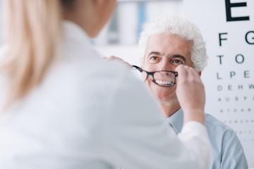 Optician giving new glasses to the patient