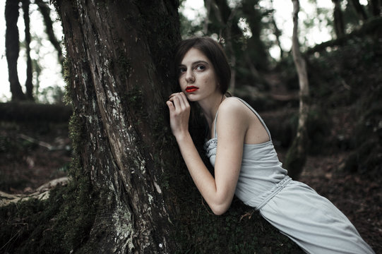 Young woman leaning against tree in forest