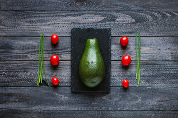 Veggie Food composition with half avocado over a darkdish