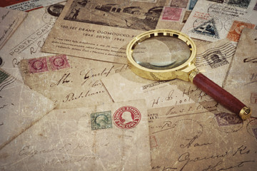 Vintage old mails, postage stamps, postcards and magnifying glass, grunge textured