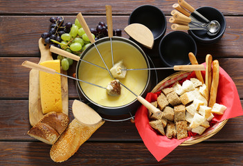 Traditional set of utensils for fondue, with bread, cheese and grapes