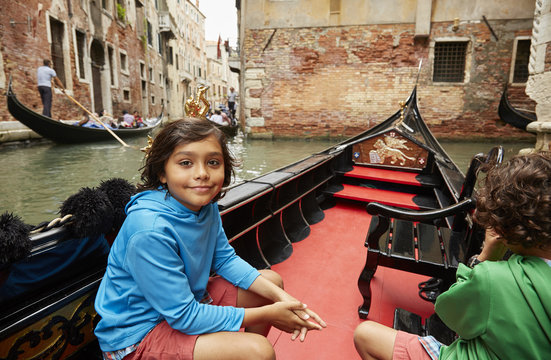 Boy sitting in gondola on Venice canal, Veneto, Italy - Powered by Adobe
