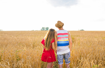 Rear view of young couple in the wheat field. Summer or autumn season, copy space