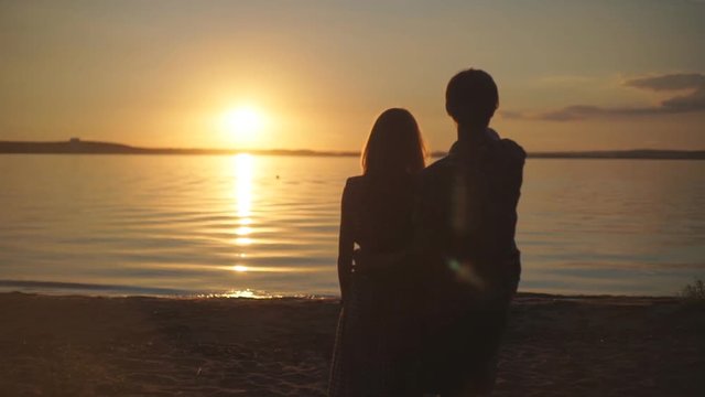 Sunset silhouette of young couple in love hugging at beach