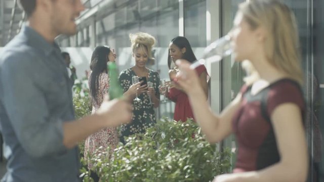  Friends socializing on city rooftop pose to take a selfie with camera phone