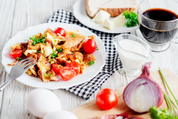 
Traditional hearty breakfast , egg omelette with herbs , tomato , onion , toast, butter , cream and black coffee on a wooden background 