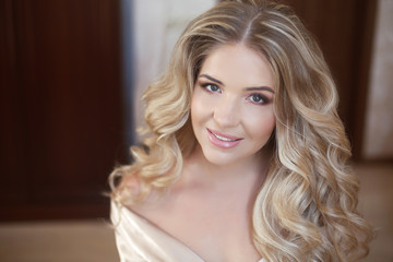 Naklejka premium Long curly hair. Beautiful blond happy smiling bride girl lookin