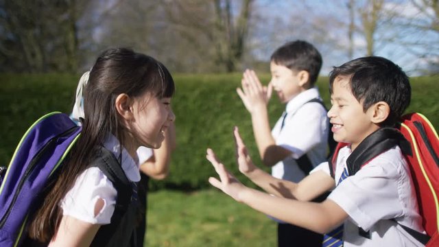  Happy young children playing pat a cake outdoors in school playground