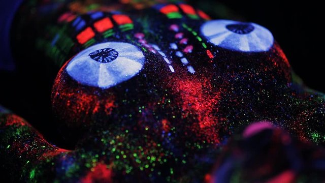 Topless girl painted in UV powder as a DJ panel.