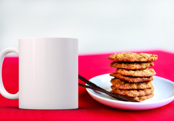 White blank coffee mug next to a plate of stacked cookies, ready for your custom design/quote.