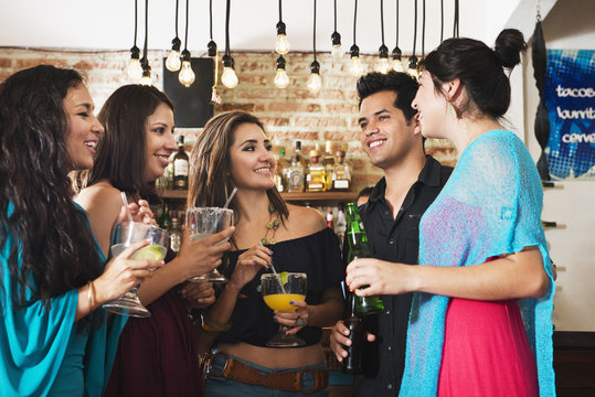 Hispanic friends having drink in bar