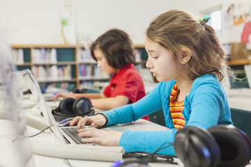 Caucasian children using laptops in library