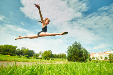 Young beautiful preteen girl doing gymnastics outdoors
