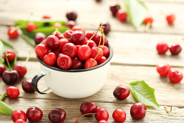 Ripe cherries in mug on a grey wooden table