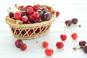 Ripe cherries in basket on a white wooden table