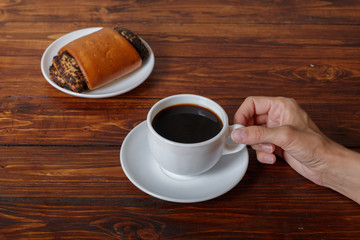 Woman's hand with cup of coffee and croissant