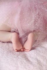 Closeup of newborn baby feet girl against soft pink blanket back
